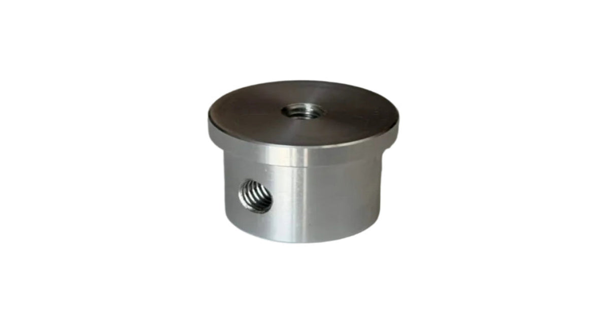 A small cylindrical metallic hardware component with a threaded hole on the side and a threaded opening on top, photographed on a plain light gray surface.