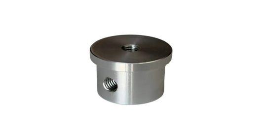 A small cylindrical metallic hardware component with a threaded hole on the side and a threaded opening on top, photographed on a plain light gray surface.